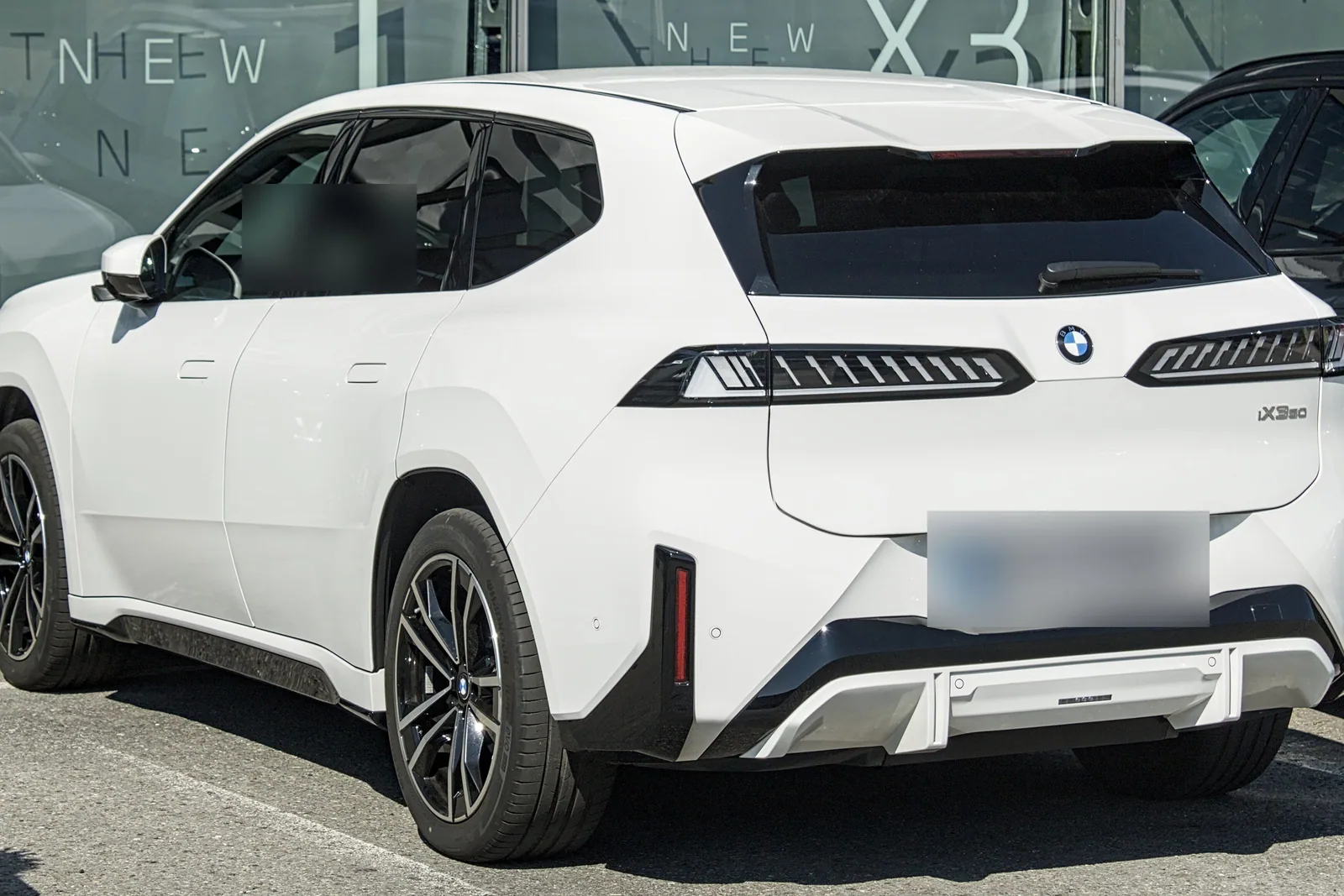 BMW iX3 Neue Klasse blanc vu de l’arrière, garé devant une concession