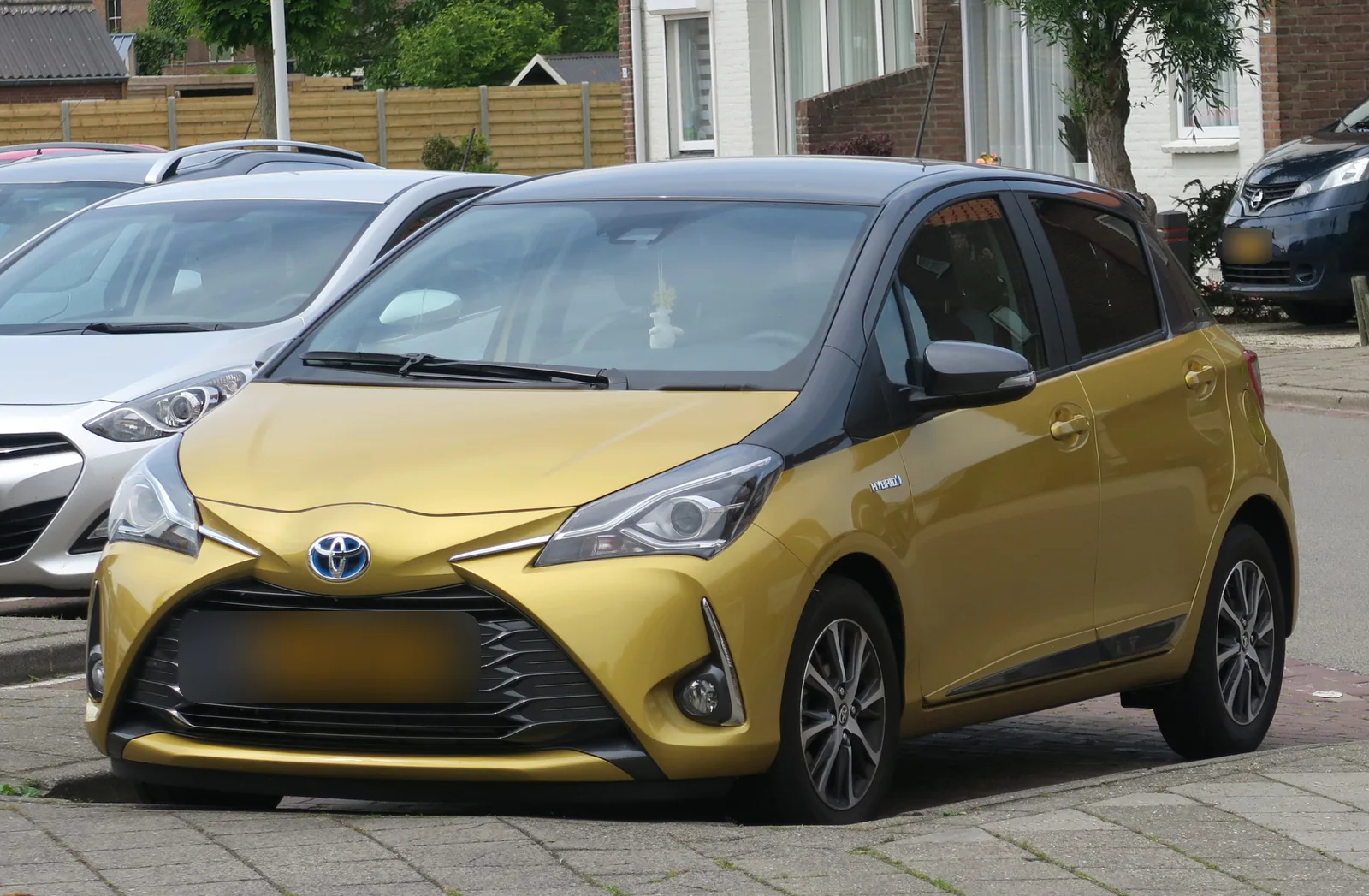 Toyota Yaris hybride de troisième génération jaune garée dans une rue, vue de trois quarts avant