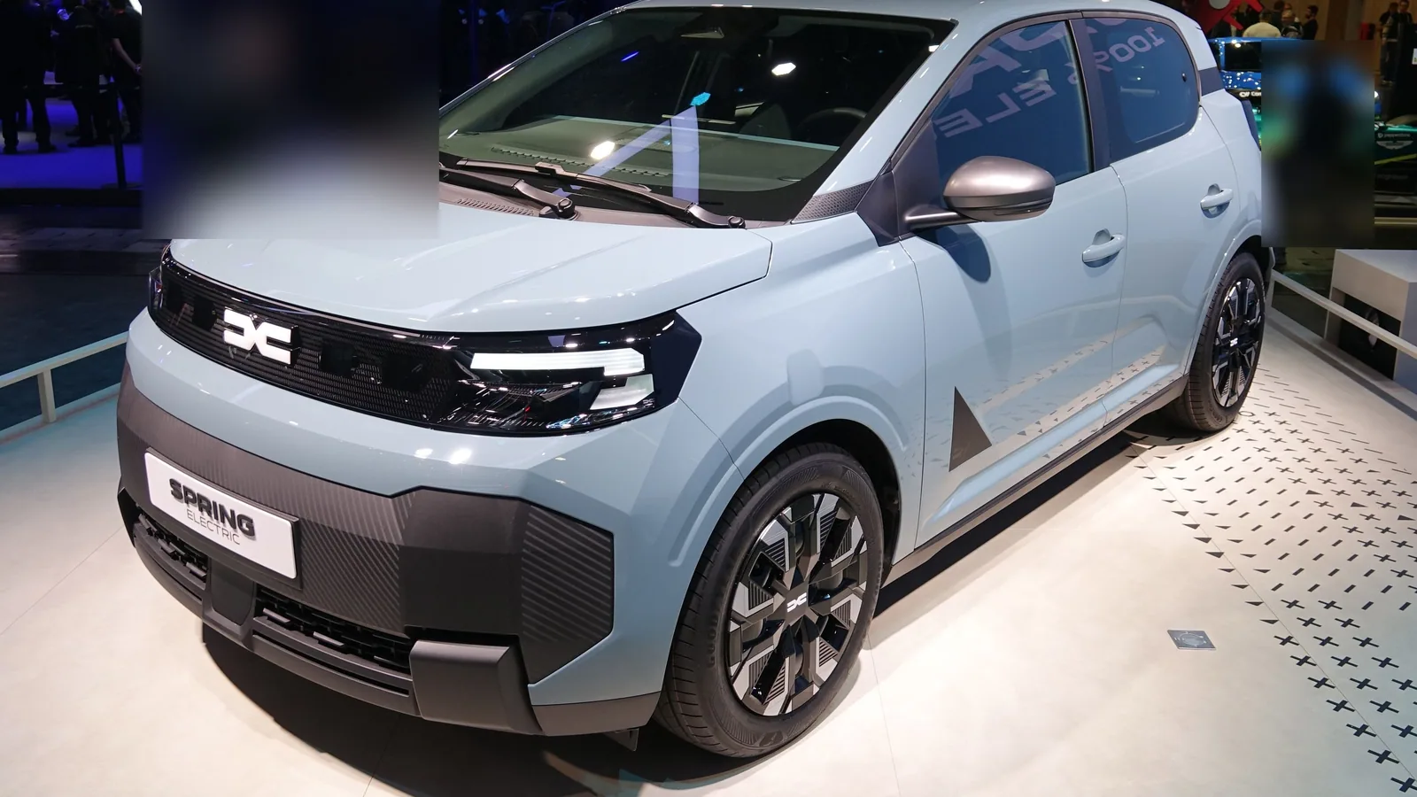 Nouvelle Dacia Spring gris clair exposée au Mondial de l’auto 2026, vue de trois quarts avant