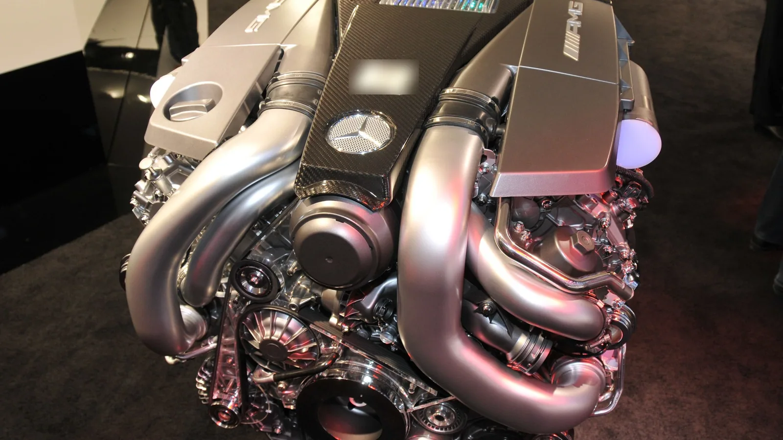 Gros moteur essence suralimenté exposé seul au Salon de Genève, capot de moteur noir et turbos chromés