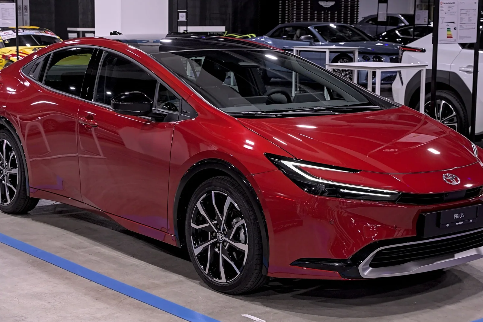 Toyota Prius de cinquième génération rouge exposée dans un salon automobile