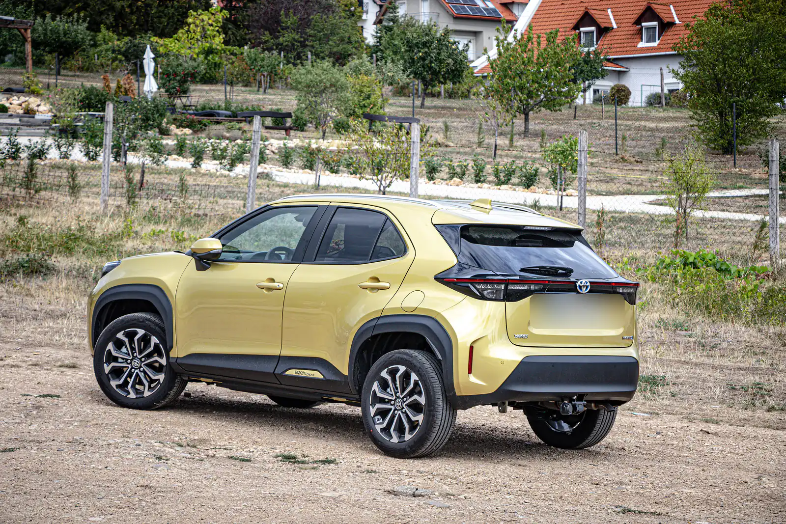 Toyota Yaris Cross jaune-vert garée dans un champ, vue de trois quarts arrière