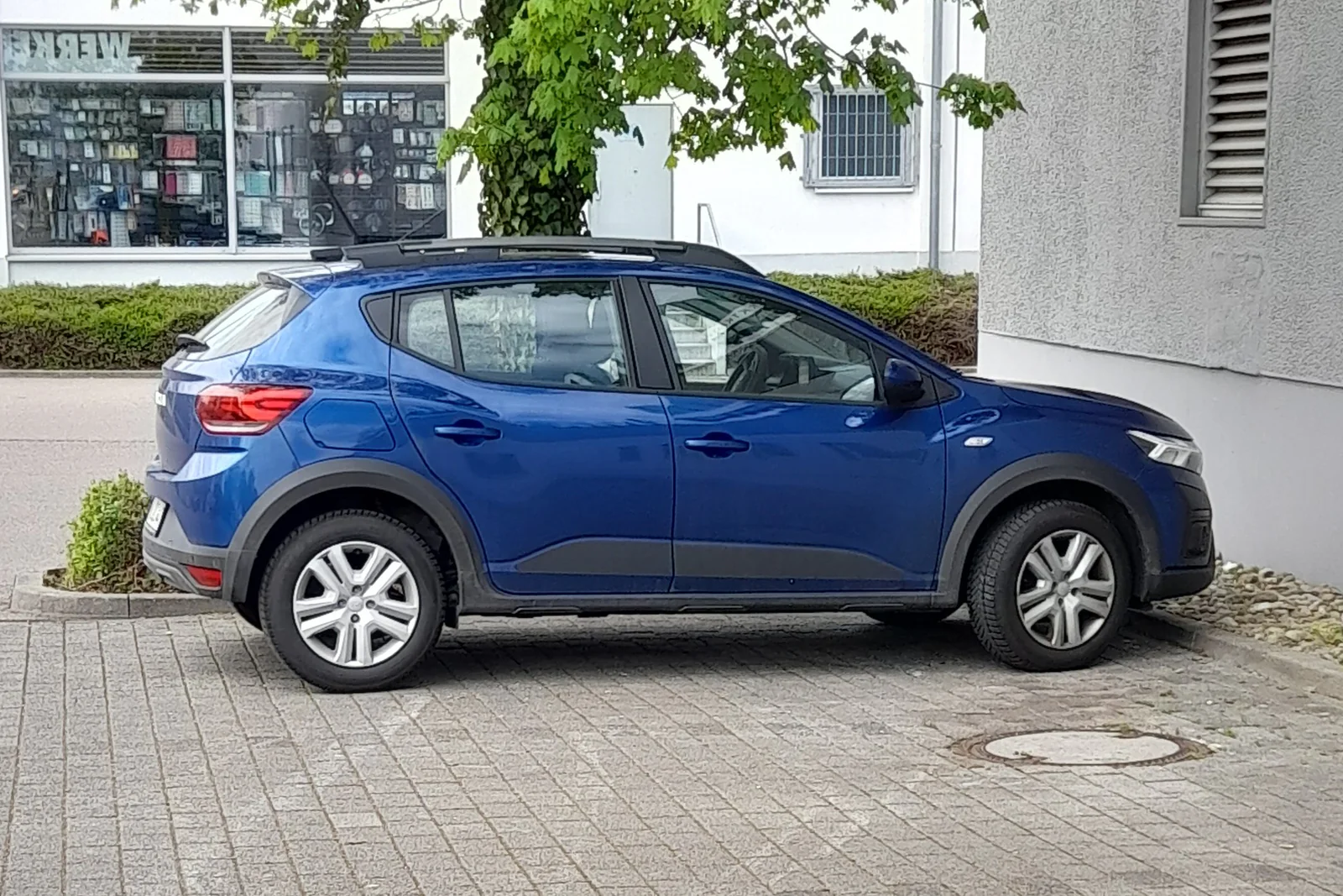 Dacia Sandero Stepway de troisième génération bleue garée dans une rue, vue de profil
