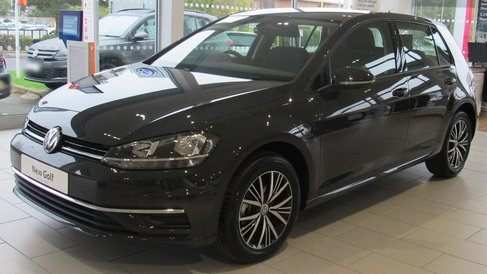 Volkswagen Golf de septième génération noire exposée dans le hall d’un concessionnaire