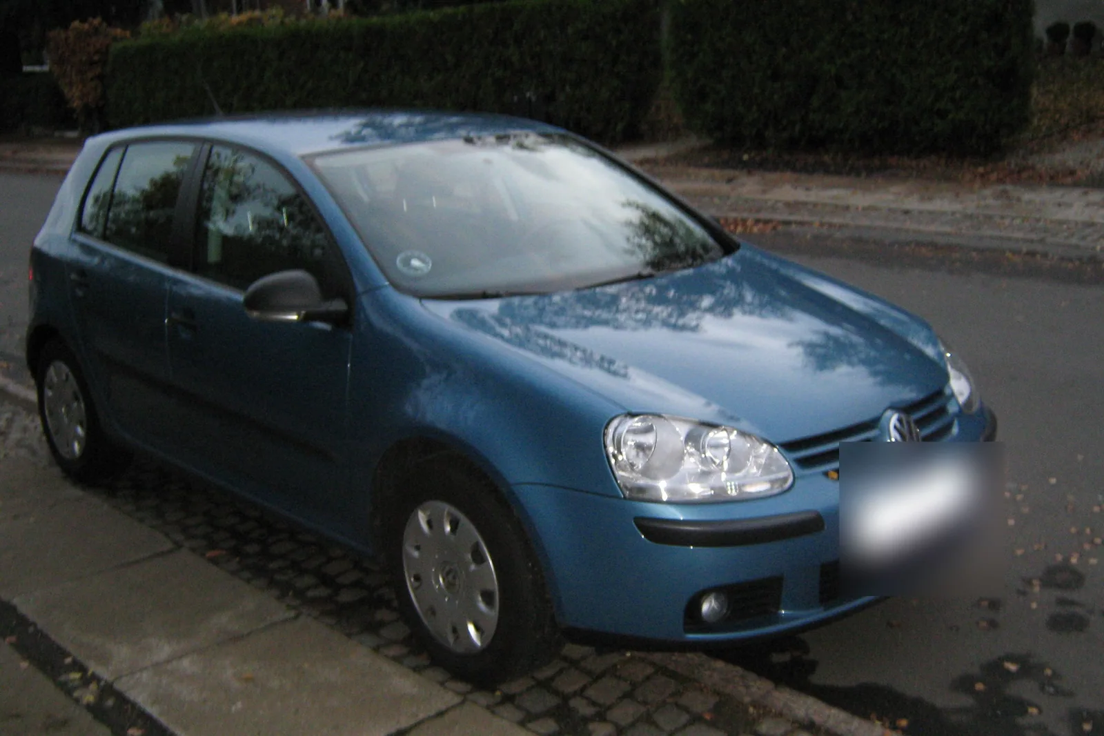 Volkswagen Golf de cinquième génération bleue garée le long d’un trottoir
