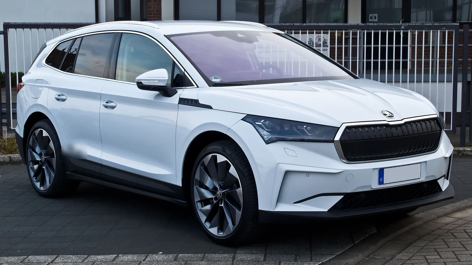 Skoda Enyaq iV 80 blanche de 2021 garée devant une clôture