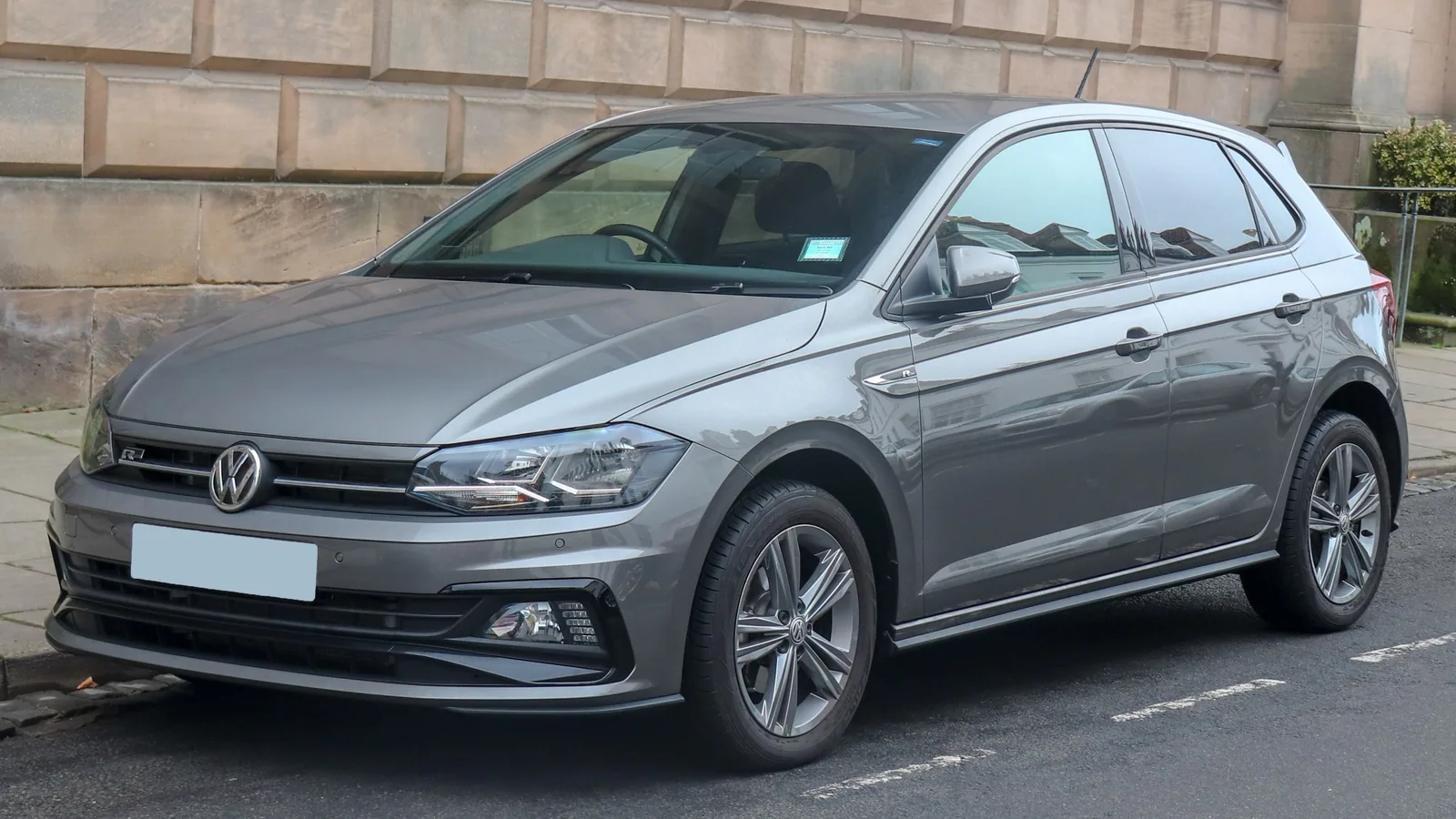 Volkswagen Polo grise de 2018 garée le long d’un mur, vue de trois quarts avant