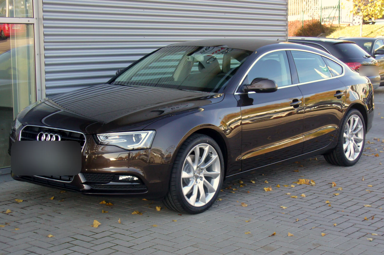 Audi A5 Sportback restylée brun foncé garée devant un bâtiment, vue de trois quarts avant