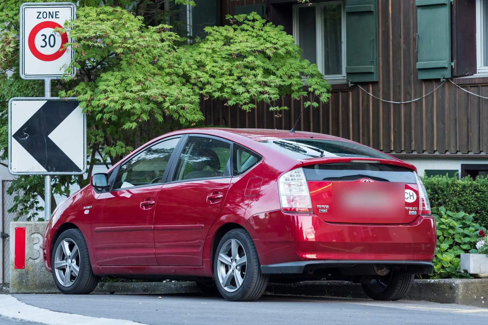 Toyota Prius rouge de deuxième génération garée dans une rue suisse