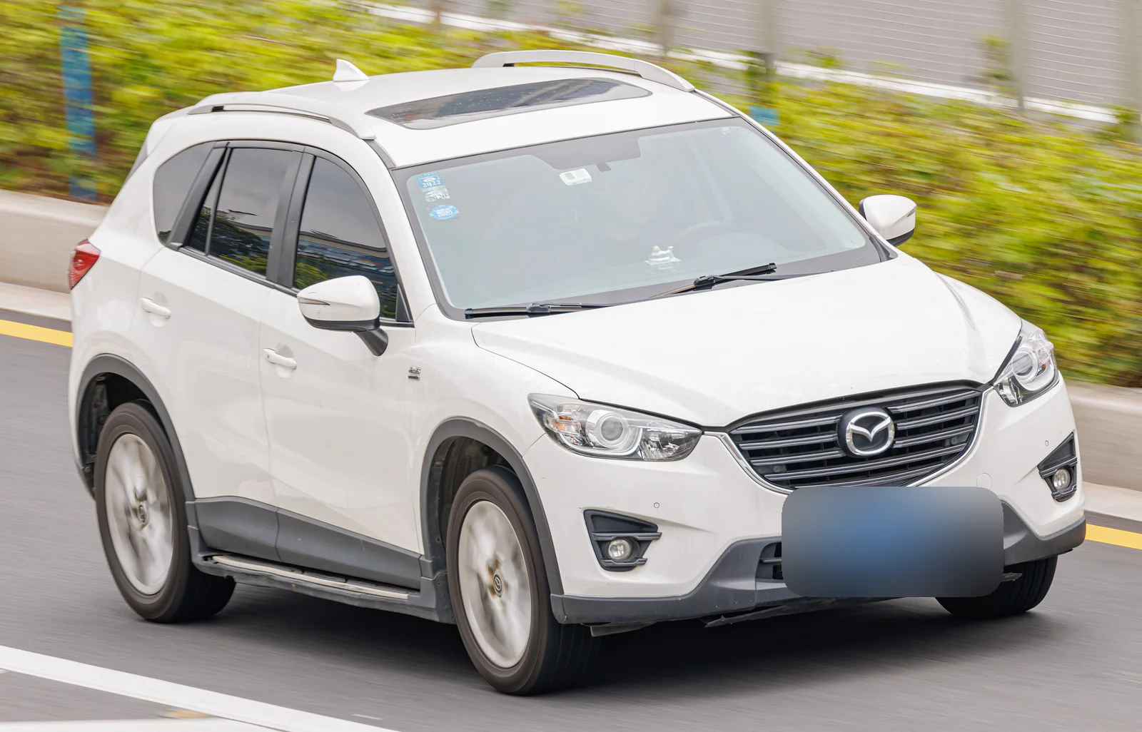 Mazda CX-5 de première génération blanc roulant en ville, vue de trois quarts avant