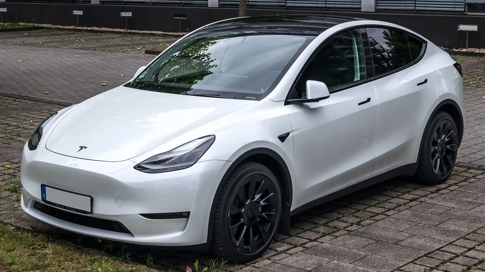 Tesla Model Y Long Range blanche d’avant le restylage, garée sur des pavés, vue de trois quarts avant