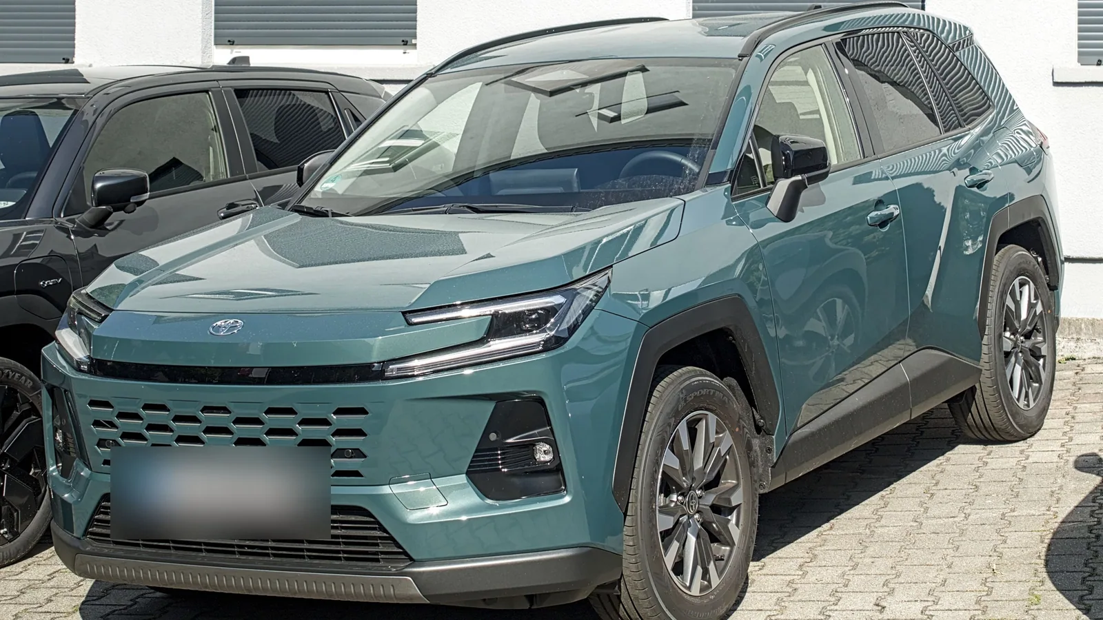 Toyota RAV4 hybride de sixième génération bleu-vert garé, vue de trois quarts avant