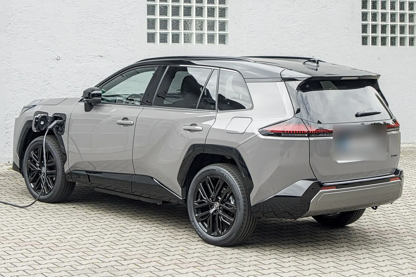 Toyota RAV4 hybride rechargeable de sixième génération en charge, vue de trois quarts arrière
