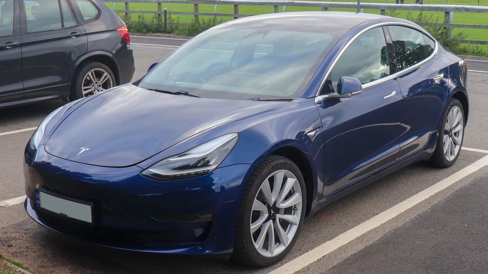 Tesla Model 3 bleue de 2019 garée sur un parking, vue de trois quarts avant