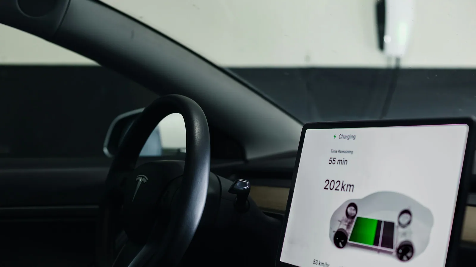 Écran central d’une voiture électrique en charge, affichant l’autonomie restante en kilomètres
