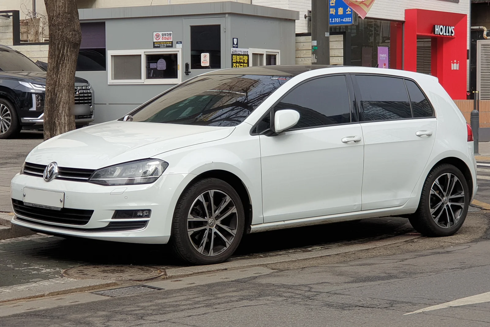 Volkswagen Golf de septième génération blanche garée dans une rue, vue de trois quarts avant